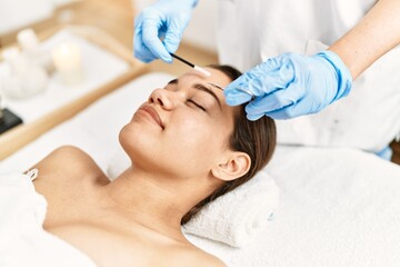 Obraz na płótnie Canvas Young latin woman relaxed having eyebrows treatment at beauty center