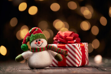 funny snowman and a box with Christmas gifts on a festive background.