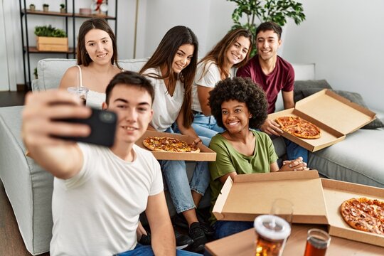 Group of young friends eating italian pizza make selfie by the smartphone at home.