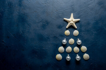 Christmas tree from sea shells and starfish on blue background, top view