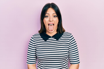 Young hispanic woman wearing casual clothes sticking tongue out happy with funny expression....