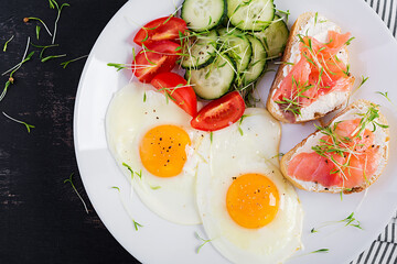 Diet breakfast. Fried eggs and sandwiches with salt salmon  and fresh salad.  Top view, overhead
