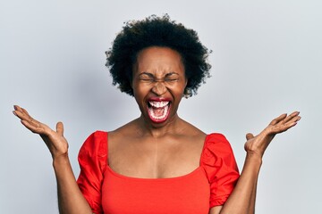 Young african american woman wearing casual clothes celebrating mad and crazy for success with arms...