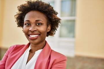 Beautiful business african american woman with afro hair smiling happy and confident outdoors at the city