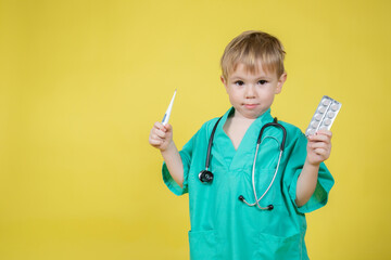 Portrait of little caucasian kid dressed in doctors coat holds pills