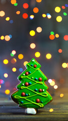 Gingerbread in shape of fir-tree. Christmas cookie at dark blurred background, soft focus, copy space.