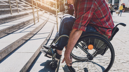 Young man with a physical disability in a wheelchair in front of the stairs