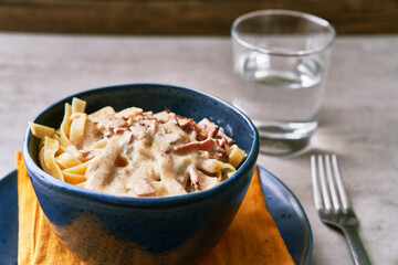  Bowl of fettuccine italian pasta with carbonara sauce on a concrete surface