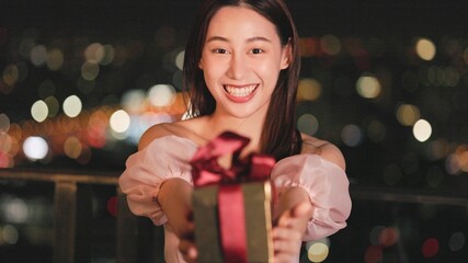 Young asian woman with sparklers is dancing and celebrating a new year. Fireworks, bengal lights in slow motion. Having fun at rooftop in the city.Happy interracial couple with glasses of wine .