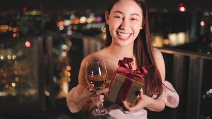Young asian woman with sparklers is dancing and celebrating a new year. Fireworks, bengal lights in slow motion. Having fun at rooftop in the city.Happy interracial couple with glasses of wine .