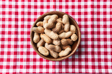  Bowl of peanuts with shell on a textile surface