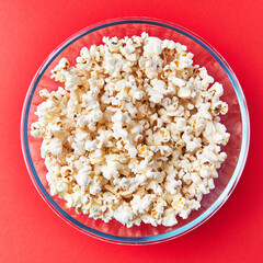  Bowl of salty popcorns on a red background