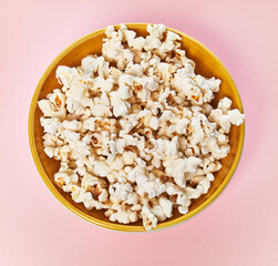  Bowl of salty popcorns on a pink background