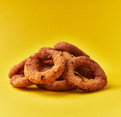  Bunch of breaded onion rings on a yellow background