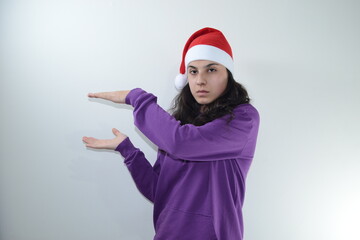 Fototapeta na wymiar Girl in red christmas hat poses in studio