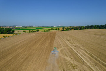 The tractor protects the ground after the harvest. Wonderful summer rural landscape. View from the drone.