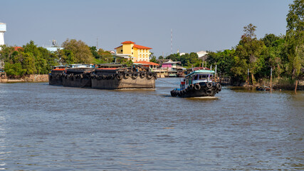 Tug boats tow barges on river in Thailand
