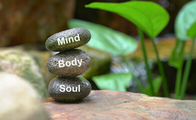 Stones stacked on top of each other. Text body mind soul on stones.
