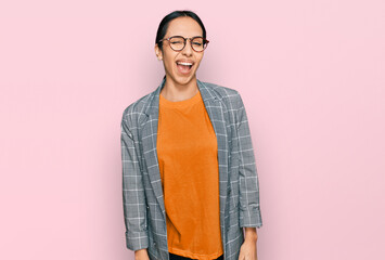 Young hispanic girl wearing business jacket and glasses winking looking at the camera with sexy...