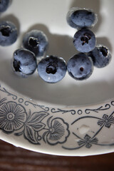 Large ripe round blue berries of blueberry. The berries are in a plate with water, cleaned. The berries are suitable for freezing or fresh consumption. Useful substitute for sweets or pastries.