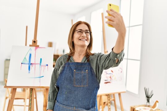 Middle age artist woman smiling happy making selfie by the smartphone at art studio.