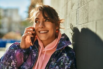 Young hispanic sporty woman talking on the smartphone drinking coffee at the city.