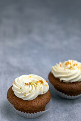 carrot cupcakes with a cream cap on a gray background
