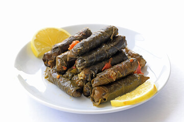 Dolma, grape leaves stuffed with rice and meat in a white plate, front view.