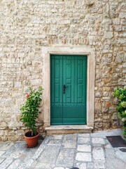 Fototapeta na wymiar Green door in the house built of a shell-rock stones