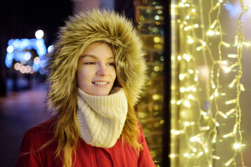 Cute young girl having fun on Christmas time in Vilnius, Lithuania. Child admiring Christmas lights.