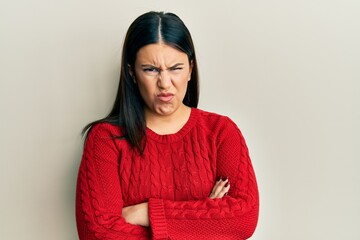 Beautiful brunette woman wearing wool winter sweater skeptic and nervous, disapproving expression on face with crossed arms. negative person.