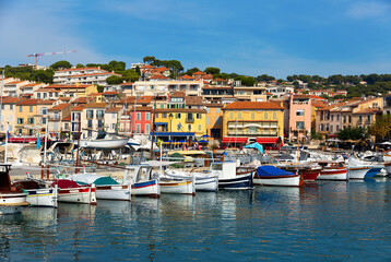 Fototapeta na wymiar Photo of harbour in French town Cassis with view of fishing boatsand and residential buildings along shore.