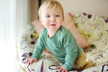 Fototapeta premium Adorable baby boy sitting in a chair by the window.