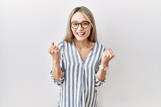 Asian young woman wearing casual clothes and glasses celebrating surprised and amazed for success with arms raised and open eyes. winner concept.