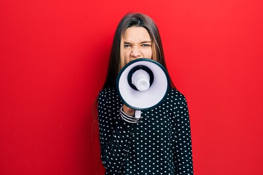 Young teenager girl shouthing and screaming with megaphone