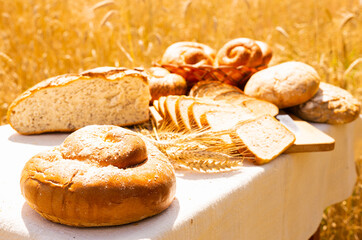 lot of different flavored bread, wheat, rye, on the table in the field outside