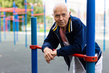 Portrait of positive elderly man in sportswear on playground
