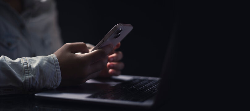 Businesswomen is working on Smartphone or Mobile and Laptop. stock business or work from home concept. dark tone.