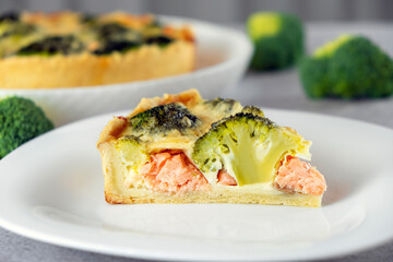 Piece of classic Quiche Lorraine pie made of shortcrust pastry with broccoli and smoked salmon. Mediterranean paleo or ketogenic healthy diet. Delicisouc dish for restaurant or cafe menu.