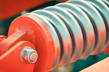 Big and hard steel silver spring as part and detail of red industrial or agricultural machine