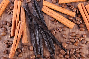 Fragrant vanilla, cinnamon sticks and coffee grains on wooden plank