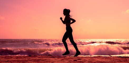 Silhouette female running on beach in sunset or sunrise time