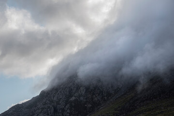 Epic mountain landscape image of Pen Yr Ole Wen in Snowdonia National Park with low cloud on peak and moodyfeel