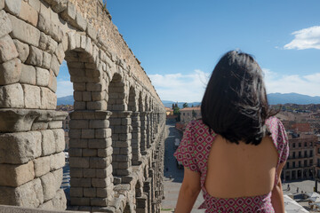 woman at Segovia acueducto viewpoint during vacation in Spain - young happy woman visiting world heritage aqueduct in Segovia enjoying holidays travel - obrazy, fototapety, plakaty