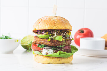 Cooking vegan burger with avocado, tomato and peanut sauce, white background with ingredients.