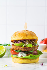 Cooking vegan burger with avocado, tomato and peanut sauce, white background with ingredients.