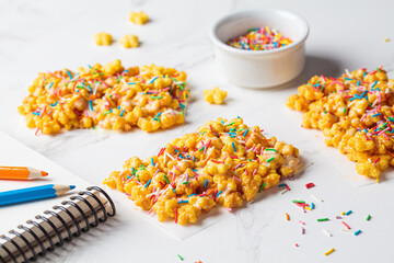 Children corn stars cereal bars with colored sprinkles and white chocolate on a white background.