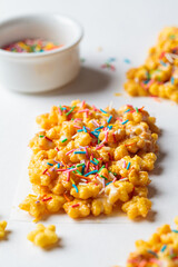 Children corn stars cereal bars with colored sprinkles and white chocolate on a white background.