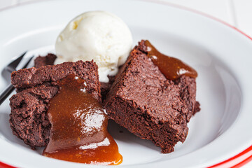 Fototapeta na wymiar Vegan brownie squares with a scoop of dairy-free ice cream and apple caramel in white plate.