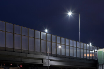 road overpass with night lighting and noise barrier - obrazy, fototapety, plakaty